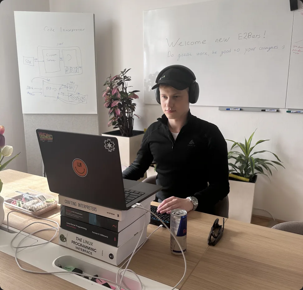New E2B hire at a desk below a “Welcome new E2Bers” whiteboard