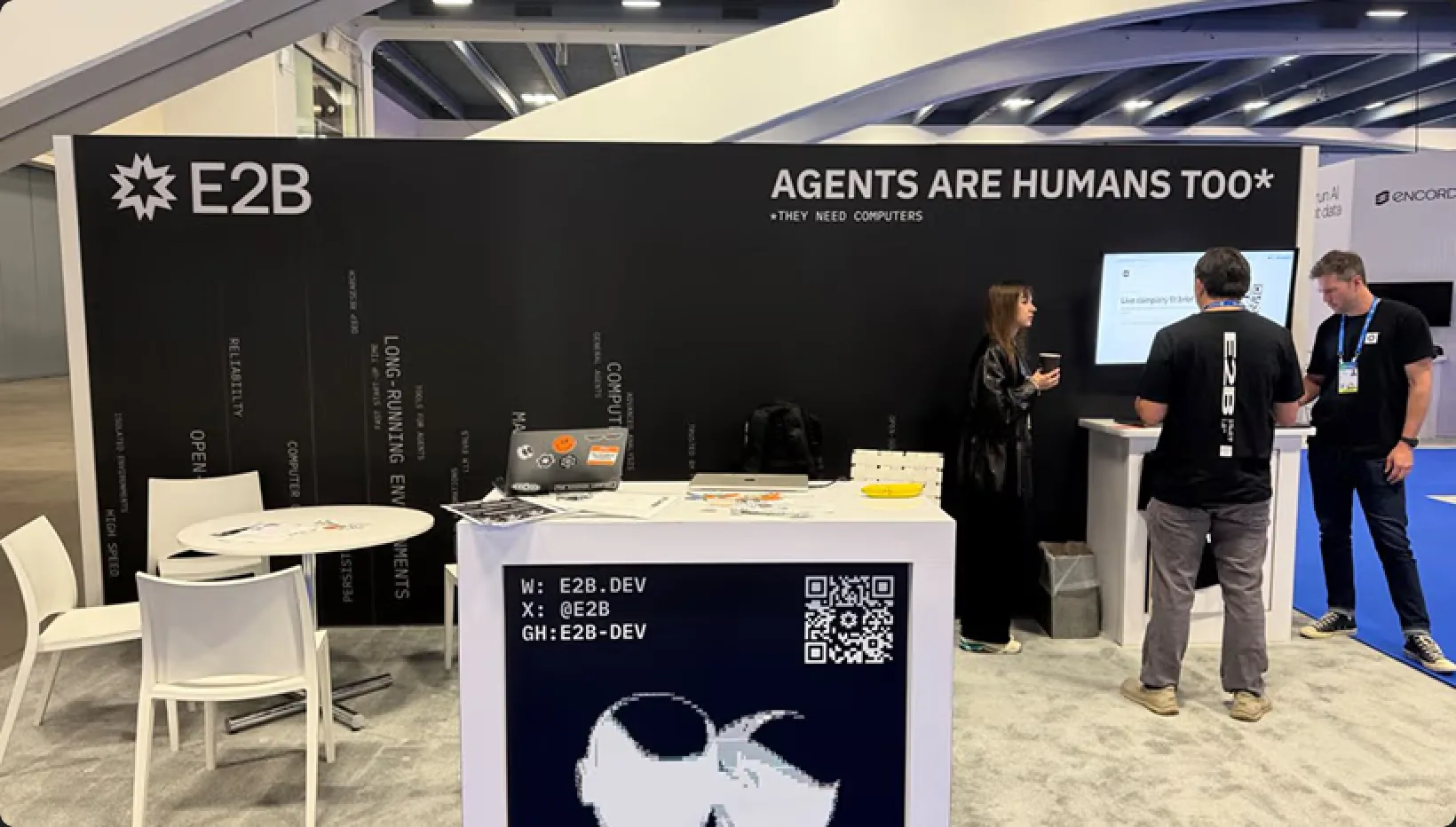 The E2B booth at a conference reading “Agents are humans too”